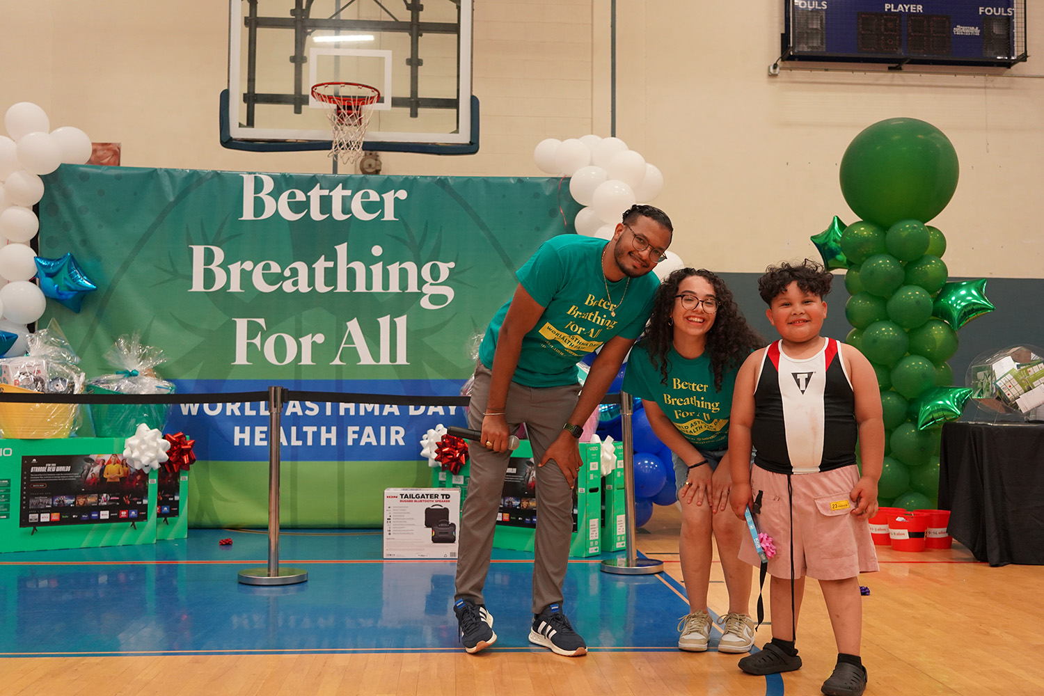 Two ATVFC members with a young boy, in front of Better Breathing For All backdrop.